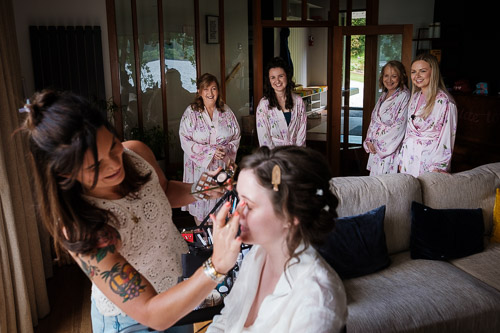 Bridesmaids look on as the bride has her makeup applied on the morning of her wedding