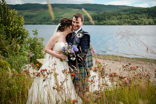 Bride and groom behind long grasses and flowers